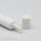 A white plastic 19mm Needle Nose squeeze tube with a narrow nozzle and a detached cap lying next to it on a plain white background. The word "COMPAX" is displayed at the bottom left corner.