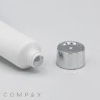 A close-up of a white 19mm Screw Top tube with its metallic cap removed. The tube lies horizontally on a white surface with the cap placed beside it, revealing the threaded opening. The brand "COMPAX" is seen in the bottom-left corner.