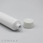 A white, cylindrical "22mm Screw Top" tube with its cap off, placed on a white surface. The threading and opening of the tube are visible, and the cap is positioned to the right of the tube. The brand name "COMPAX" is printed in gray at the bottom left corner.