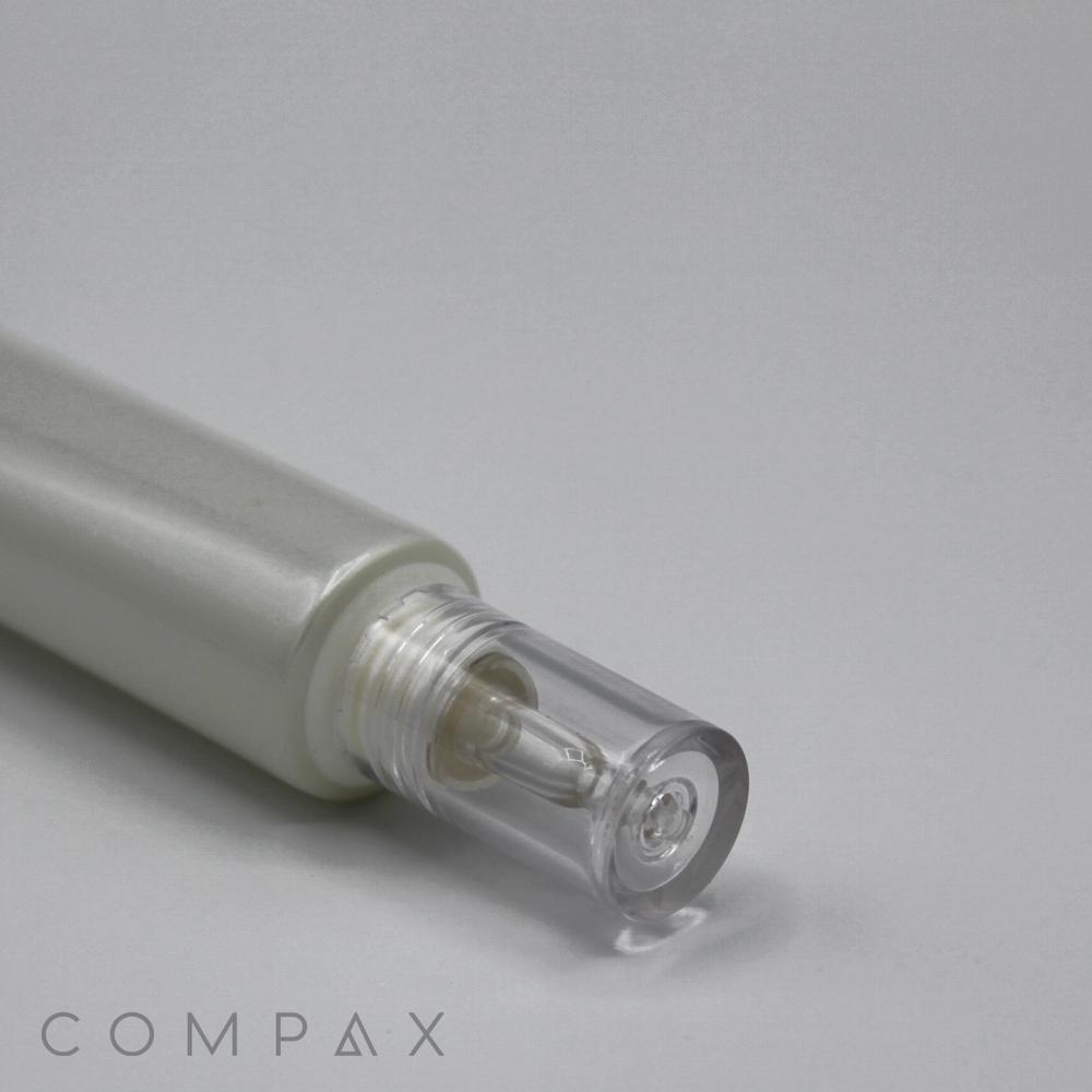 A close-up photo of a silver and transparent cosmetic bottle with a clear cap, laying horizontally. The brand name "COMPAX" is visible in the bottom left corner. The background is plain white. This product is labeled as the "25mm Dropper Tip.