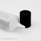 A close-up image of a transparent plastic bottle lying horizontally with a thin, 25mm Needle Nose tip exposed. The black bottle cap is positioned beside the nozzle. The background is a clean, white surface. The word "COMPAX" is visible in the bottom left corner.