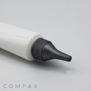 A close-up of a white tube with a black pointed nozzle, labeled "30mm Needle Nose Twist," laid on its side against a plain light gray background. The bottom-left corner of the image features the word "COMPAX" in a subtle gray font.