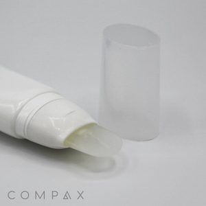 A close-up image of a 30mm Oval Silicone Brush Twist with a transparent gel-like substance emerging from its nozzle. The tube's clear cap is placed off to the side, and the bottom-left corner features the text "COMPAX." The background is plain white.