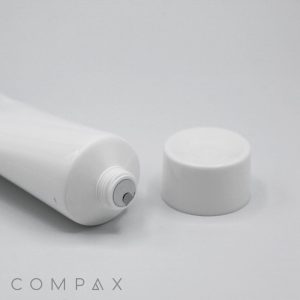 A white tube of the 35mm Screw Top product lying on its side with the cap removed and placed next to it on a plain, light background. The word "COMPAX" is written at the bottom left corner of the image.