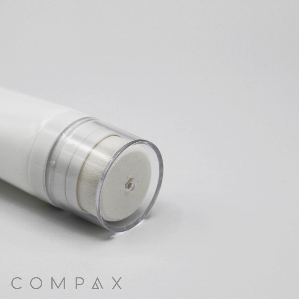 A close-up image of a white cylindrical 35mm Sponge Applicator with a transparent cap, lying on its side. The bottom part of the applicator is in focus, while the upper part is slightly blurred. The word "COMPAX" is visible in the bottom left corner of the image.