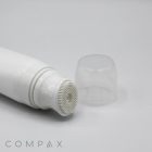 A 40mm Silicone Brush Applicator featuring a white cylindrical tube with a textured, bristled applicator tip is shown lying on a white surface. The transparent cap is off and placed next to the tube, with the word "COMPAX" displayed in the bottom left corner.