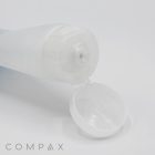 A 40mm Flip Top open, translucent white plastic squeeze bottle lies on its side with its flip-top cap open, revealing a small dispenser nozzle. The word "COMPAX" is printed in gray at the bottom left corner. The background is white.