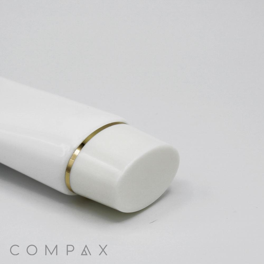 Close-up of a 40mm Oval Screw Top in a white tube with a gold ring near the cap, shown on a light gray background. The word "COMPAX" is positioned at the bottom left corner.