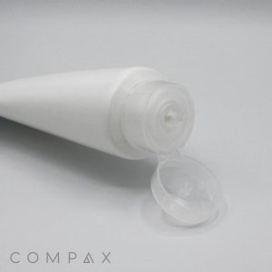 A close-up photo of an open white plastic squeeze tube with a clear flip-top cap, lying on its side. The tube is positioned diagonally, with the opening and cap visible in the foreground. The product name "50mm Flip Top" is printed in small letters at the bottom left corner.