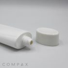 Close-up of an open 50mm Oval Screw Top tube lying horizontally, with its white cap placed separately beside the opening. The background is plain white, and "COMPAX" is written in gray text at the bottom left corner of the image.