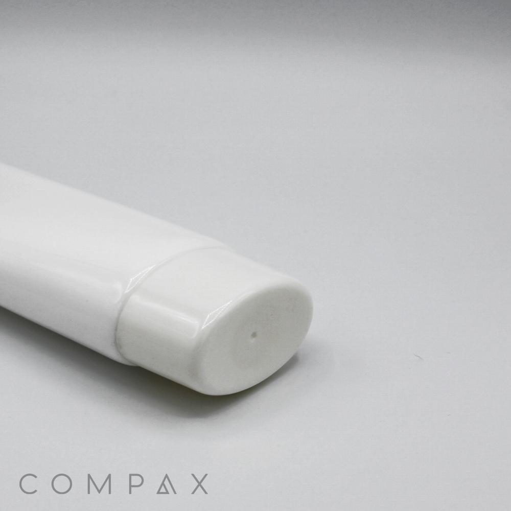 A close-up image of a white, cylindrical tube with a rounded cap, designed for containing lotion or cream. The phrase "COMPAX" is printed in grey letters on the bottom left corner of the image. The background is plain and light-colored. This product is identified as the 50mm Oval Screw Top.