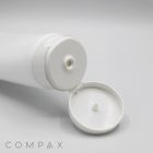 A 60mm Flip Top white plastic squeeze bottle with a flip-top lid is open, revealing the nozzle opening. It is positioned on a white background, and the brand name "COMPAX" is visible in the bottom left corner.