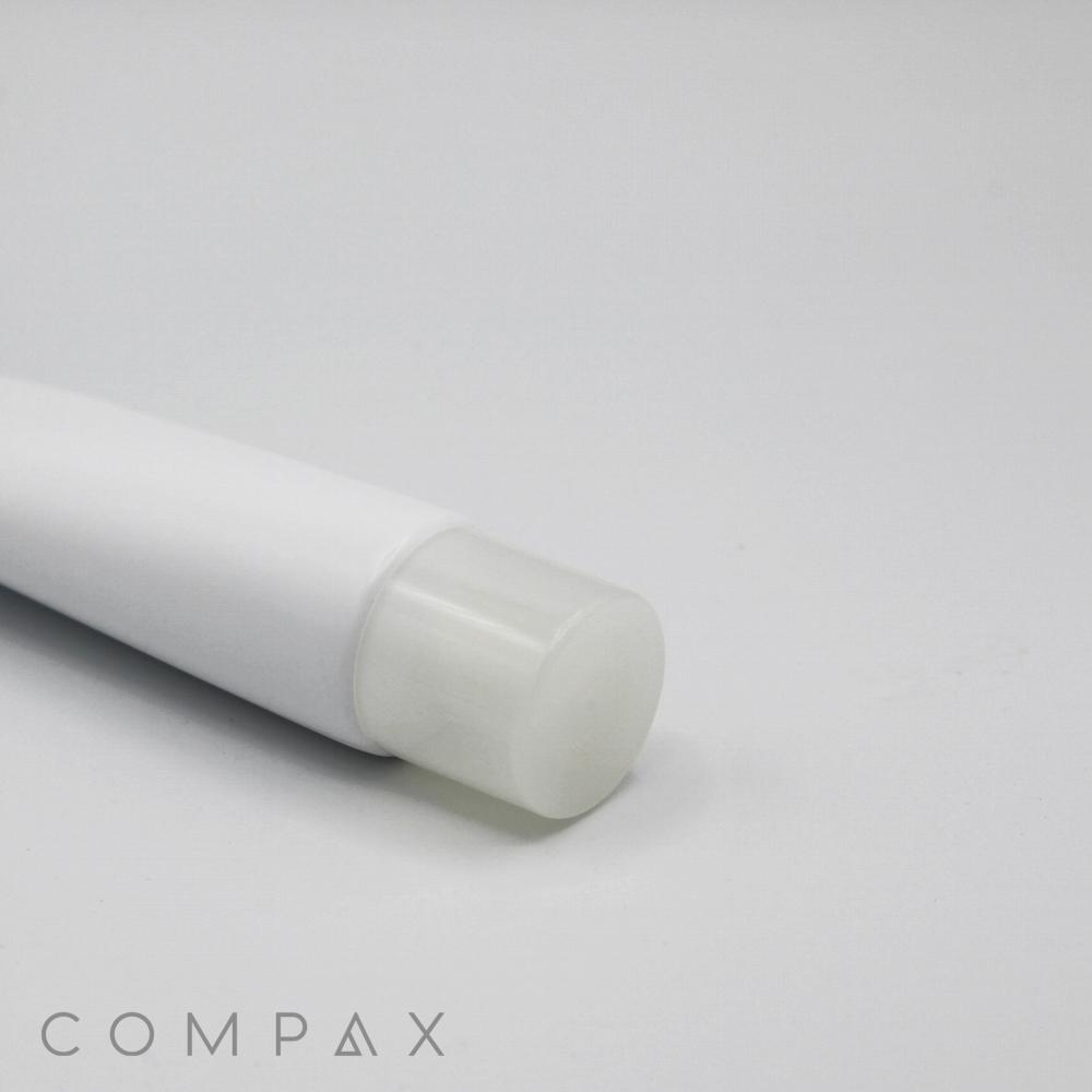 A close-up image of a white, cylindrical tube with a clear cap, likely containing a cosmetic product. The words "30mm Needle Nose" and "COMPAX" are visible at the bottom left corner of the image on a plain, light gray background.