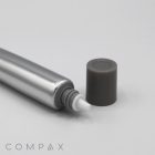 A 19mm Needle Nose, a silver cylindrical object with a white nozzle at one end and a dark grey cap removed and placed to the side, all set against a white background. The word "COMPAX" is visible in light grey text at the bottom left corner of the image.