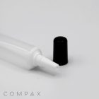 A close-up image of a white plastic tube labeled "16mm Needle Nose" with an open nozzle, laying horizontally on a white surface. The tube's black cap is placed beside it. The word "COMPAX" is lightly visible in the bottom left corner.