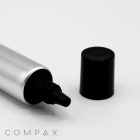 A silver tube, labeled "22mm Needle Nose," lies horizontally with its black cap removed and placed beside it. The tube's nozzle is visible, and the name "COMPAX" is displayed in the bottom-left corner. The background is plain white.