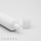 A 25mm Needle Nose tube with a pointed nozzle lies on its side against a white background. The cap, removed from the nozzle, is placed next to the tube. The word "COMPAX" is visible in gray text at the bottom left corner of the image.