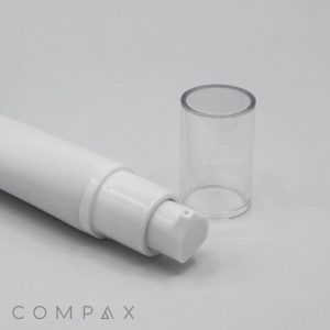 A white cylindrical 25mm Airless dispenser with a clear plastic cap removed, showcasing the pump nozzle. The cap is placed next to the dispenser on a plain white surface. The word "COMPAX" is visible in the bottom left corner.