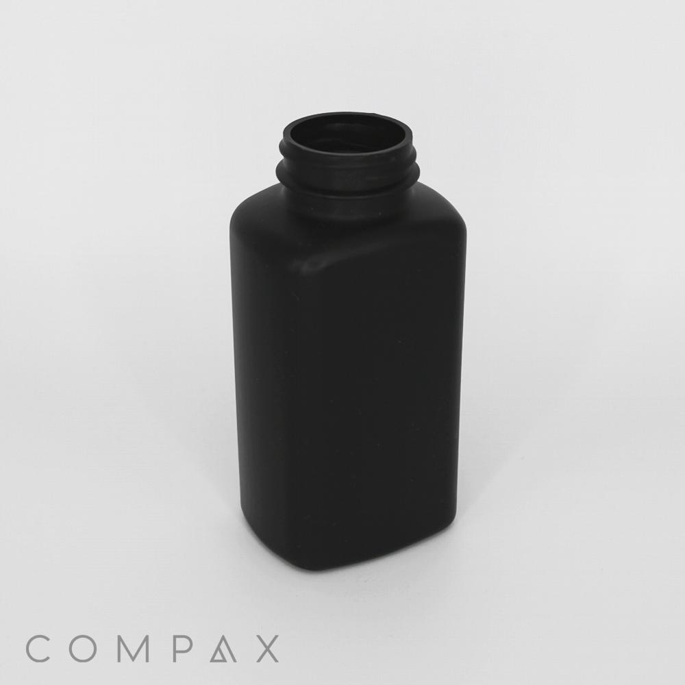 A black, rectangular plastic bottle with a threaded neck, suitable for holding liquids. The bottle is standing upright on a white surface. The word "COMPAX" is faintly visible at the bottom left corner.