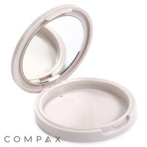 The Single Well Round Compact with Mirror features a compact design with an open lid that reveals a circular mirror on the inside. The lower compartment is empty, designed to hold makeup products such as powder or foundation. The case boasts a white, smooth, and glossy finish.