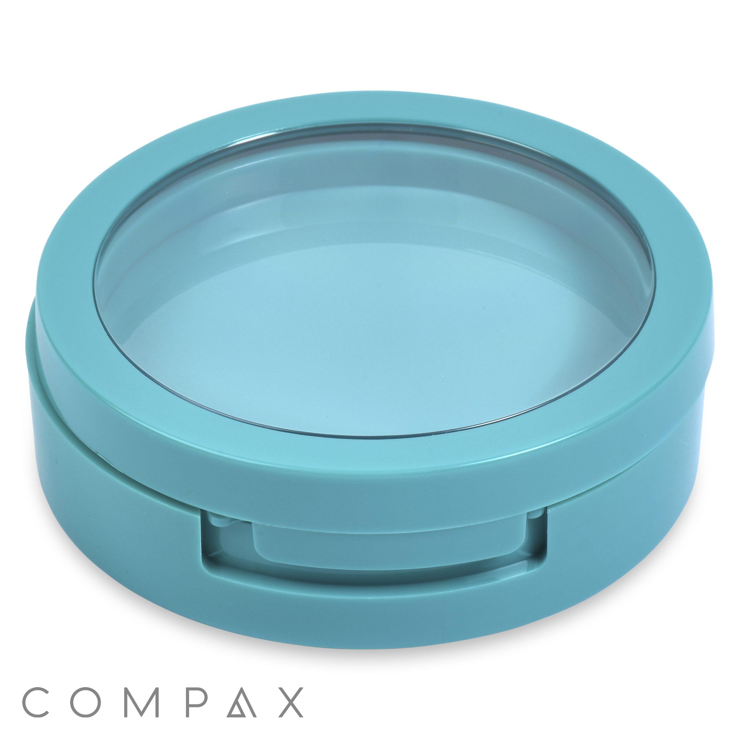 The Single Pan Round Compact is a turquoise container with a transparent lid. It features a small, built-in hinged handle on the front side, which seems to assist with opening and closing. The securely fitted lid suggests it’s ideal for storage or organization.