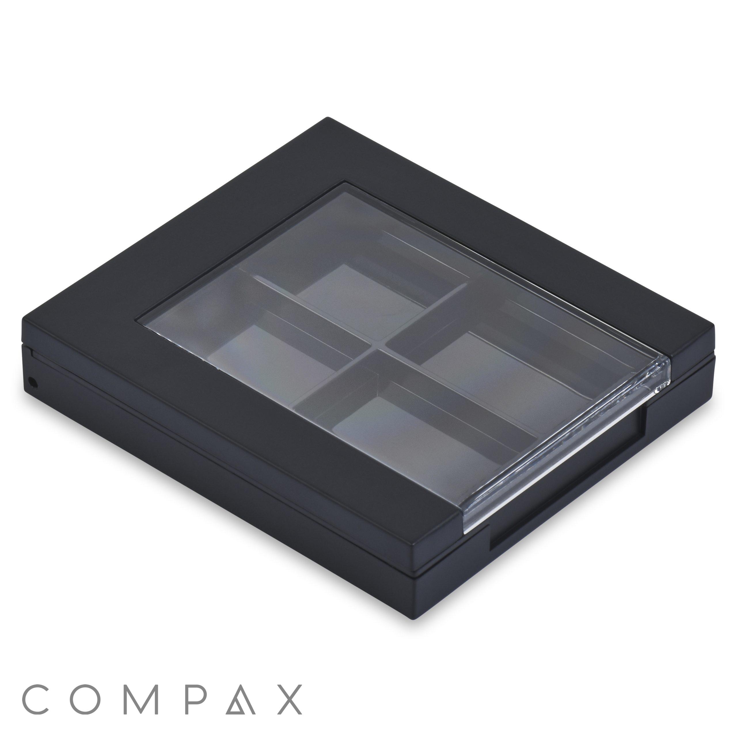 The 4 Well Square Compact is a sleek, minimalist black makeup palette case with a transparent top that reveals its four inner compartments. Its smooth edges and modern design make it an elegant accessory. The compact is showcased lying flat against a plain white background.