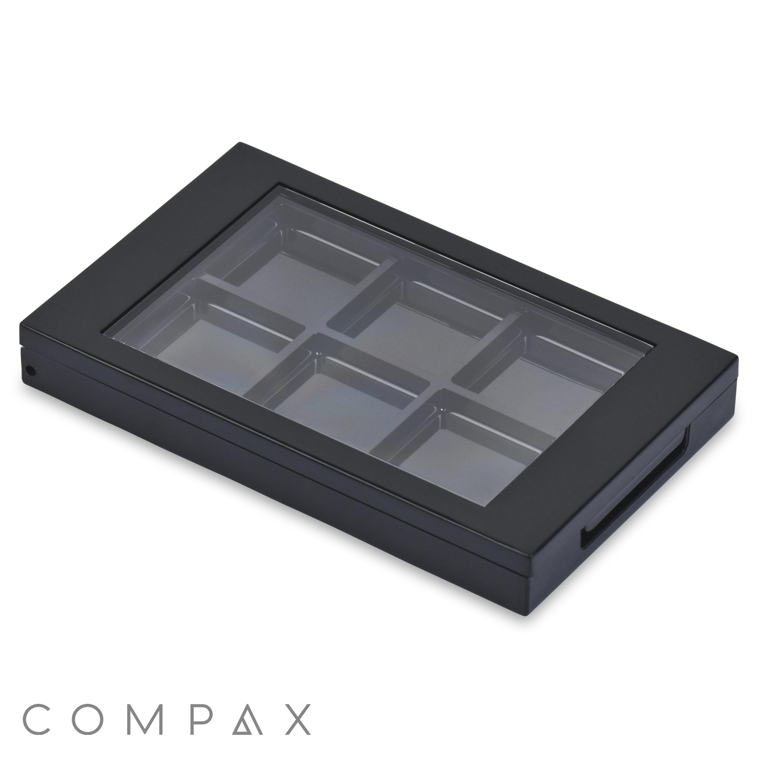 A "6 Well Rectangular Compact" in black, featuring a transparent glass top cover. The top-angle view reveals its six empty compartments and a side handle on the right.