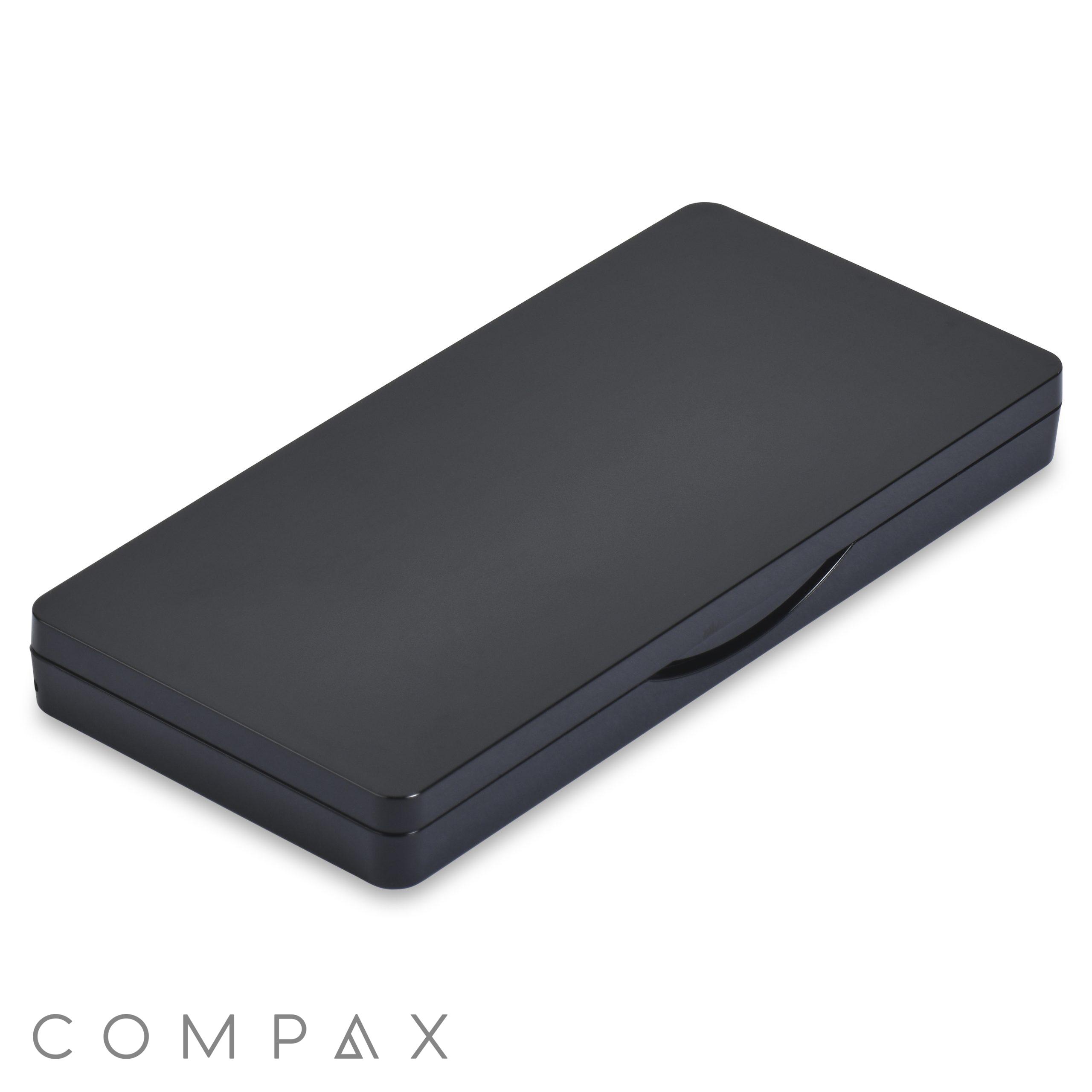 A sleek Single Pan Rectangular Compact with Mirror, featuring a black metal case with rounded corners, closed and lying flat. Its surface is smooth with a subtle glossy finish and has a slight indentation along the opening edge, hinting at a clasp or handle for easy opening.