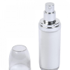 A white cylindrical pump bottle with a silver dispenser and a clear, round cap placed beside it.