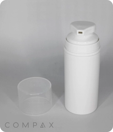 A white cylindrical pump bottle stands upright with its translucent cap placed beside it. The bottle is plain with no labels or markings. The word "COMPAX" is printed at the bottom of the image. Note: this image is a render.