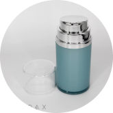 A blue and silver cylindrical cosmetic bottle with a shiny pump dispenser and a clear plastic cap placed next to it on a white surface.
