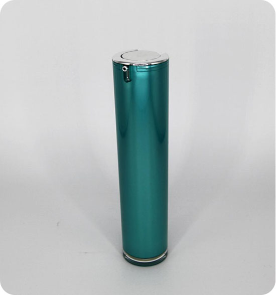 A cylindrical, teal-colored metallic pump bottle with a silver top and bottom is centered against a plain white background. The top features a small spout opening mechanism. The design is sleek and modern.