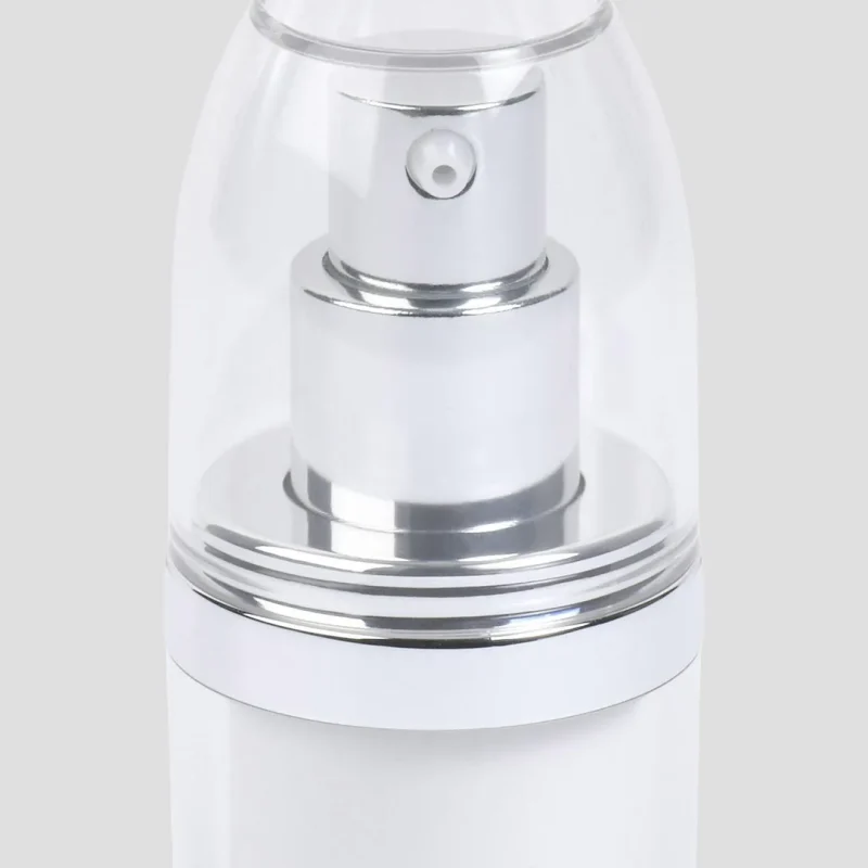 A close-up of a sleek, white cylindrical spray bottle with a silver pump. The pump is covered by a transparent plastic cap. The bottle has a minimalist design and stands against a plain gray background.