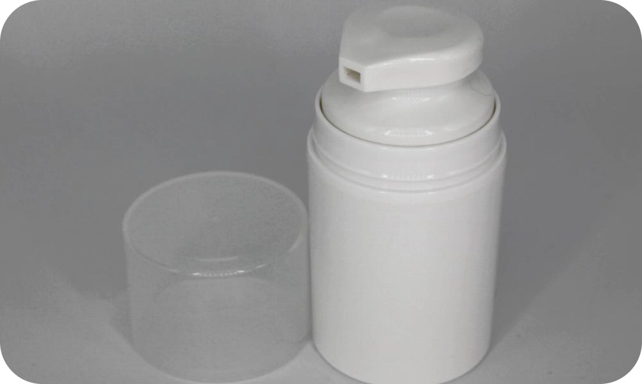 A white plastic pump bottle with a transparent cap placed beside it on a plain gray background. The bottle is cylindrical and the cap is slightly larger than the bottle's neck. The pump is in a closed position.
