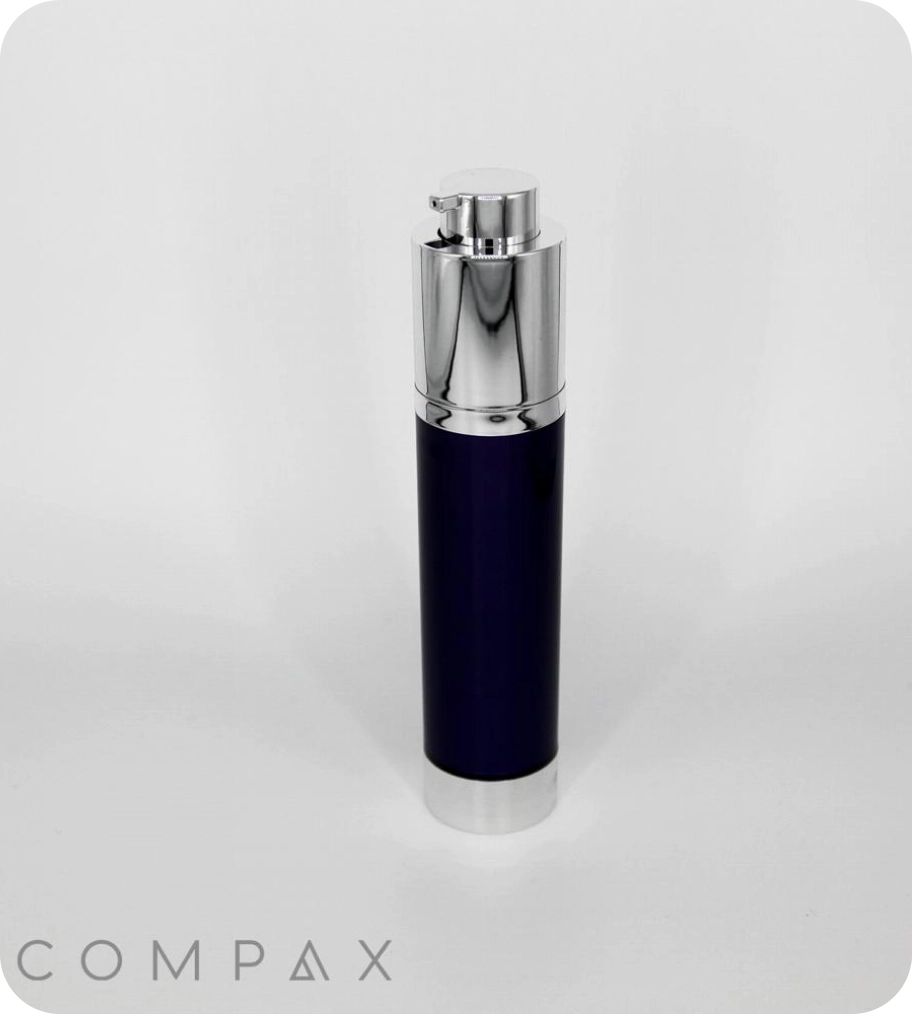 A sleek, cylindrical bottle with a shiny silver cap and a dark body stands upright against a plain white background. The word COMPAX is visible in the bottom left corner.